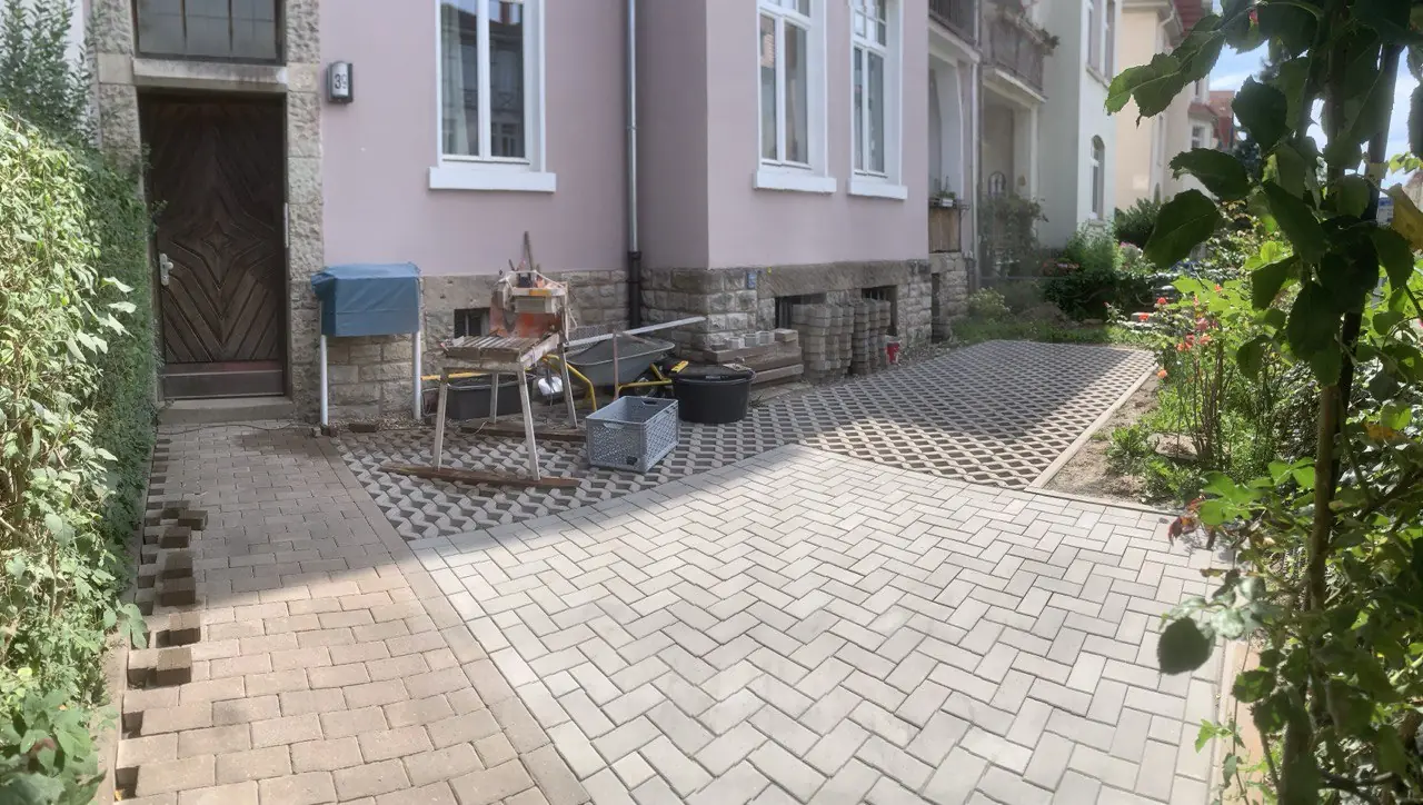 Frisch gepflasterter Hof im Fischgrätmuster vor einem Wohnhaus